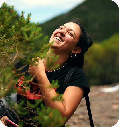 A young woman laughing among trees on a hillside
